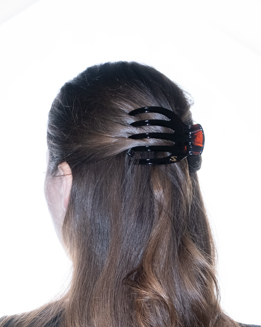 Black hair clip in a young black hair models hair on a white background