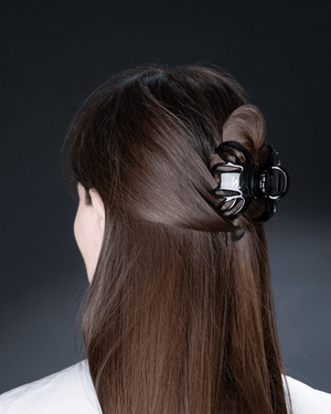 Sacrae Lena claw clip glossy black — worn at the temple, minimal styling