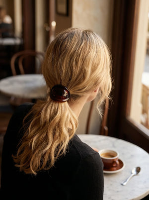Model wearing Sacrae Charmé de Cheveux hair elastic in Tortoise, ponytail, café window light