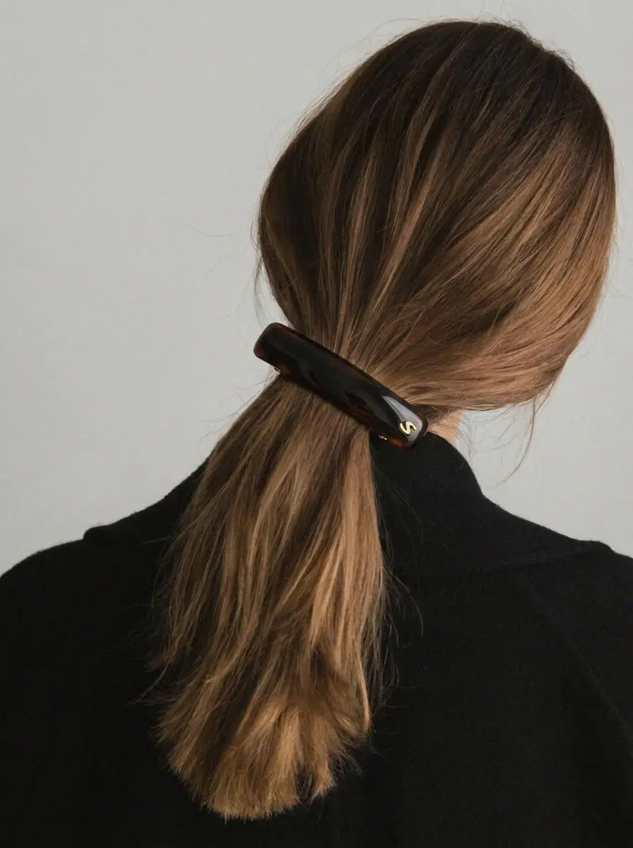 Model wearing Sacrae Jonc Classique Barrette in Tortoise, low ponytail, back view