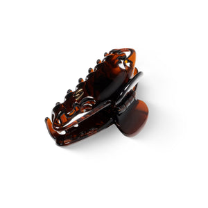 Melissa Large Claw Clip tortoise — flatlay on dark surface, editorial angle