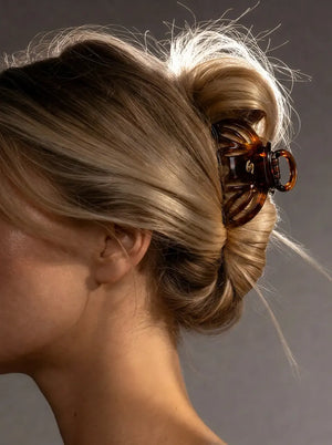 Model wearing Sacrae Lena Small Claw Clip in Tortoise, bun hairstyle, side view
